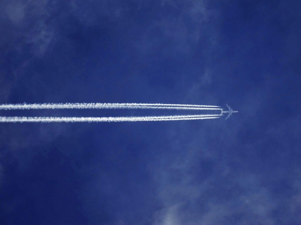 Home A jet airplane leaves contrails in a clear blue sky, symbolizing speed and modern aviation.