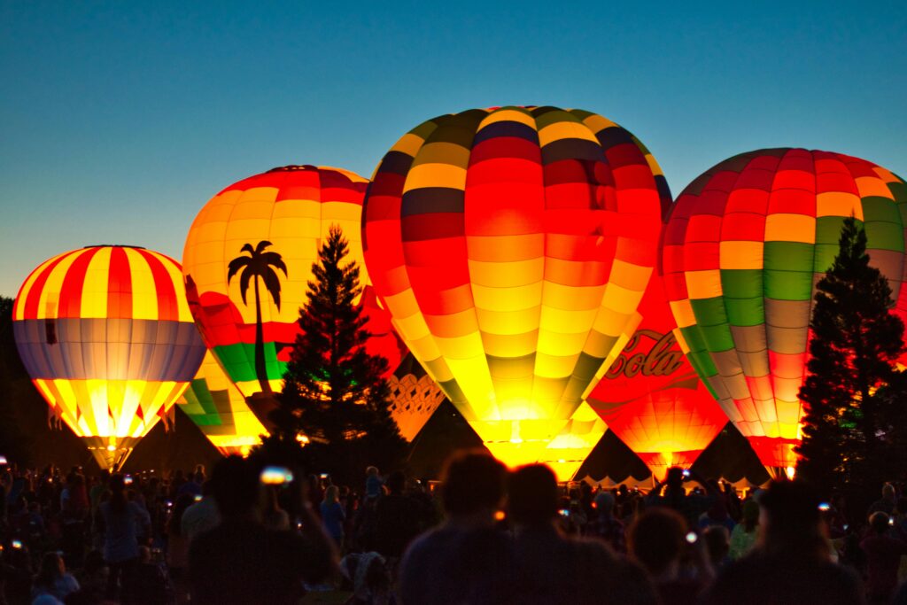 Home Vibrant hot air balloons light up the night sky at a joyful outdoor festival.